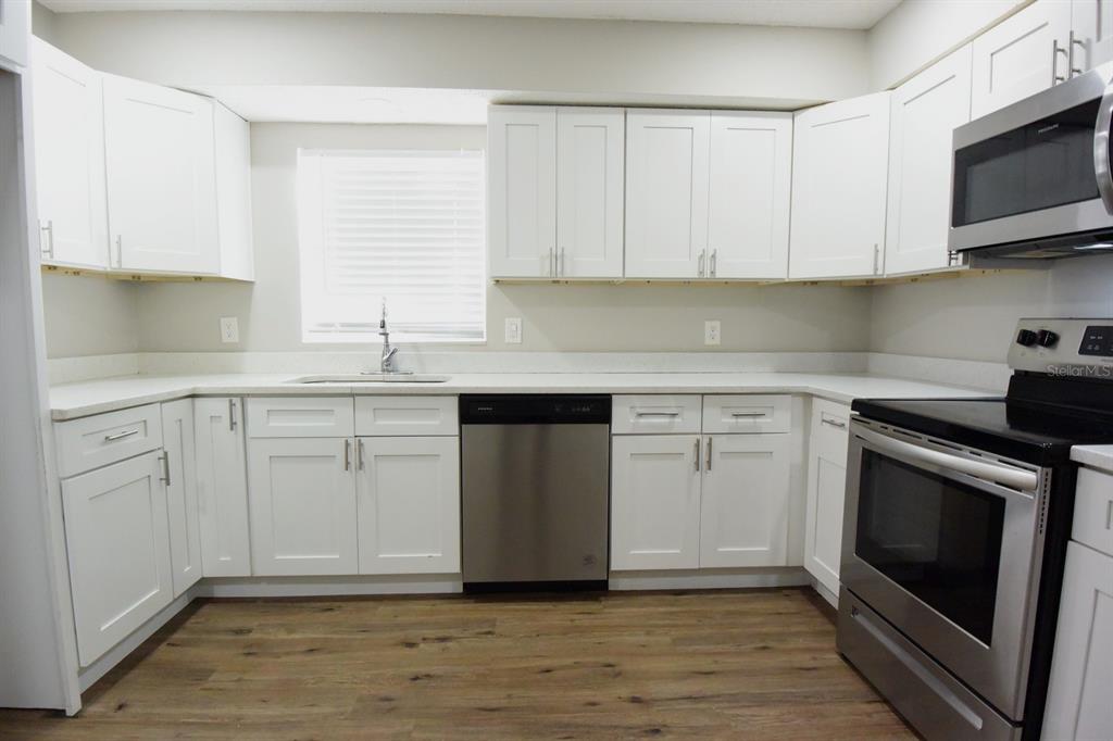 5845 Elm Street New Port Richey, FL 34652 - Photo 8 of 38 a kitchen with white cabinets stainless steel appliances and sink