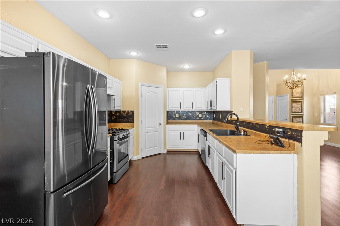 8934 Deep Ridge Court Las Vegas, NV 89178 - Photo 9 of 47 A streamlined kitchen presents stainless steel appliances and abundant white cabinetry with a rich wood floor.