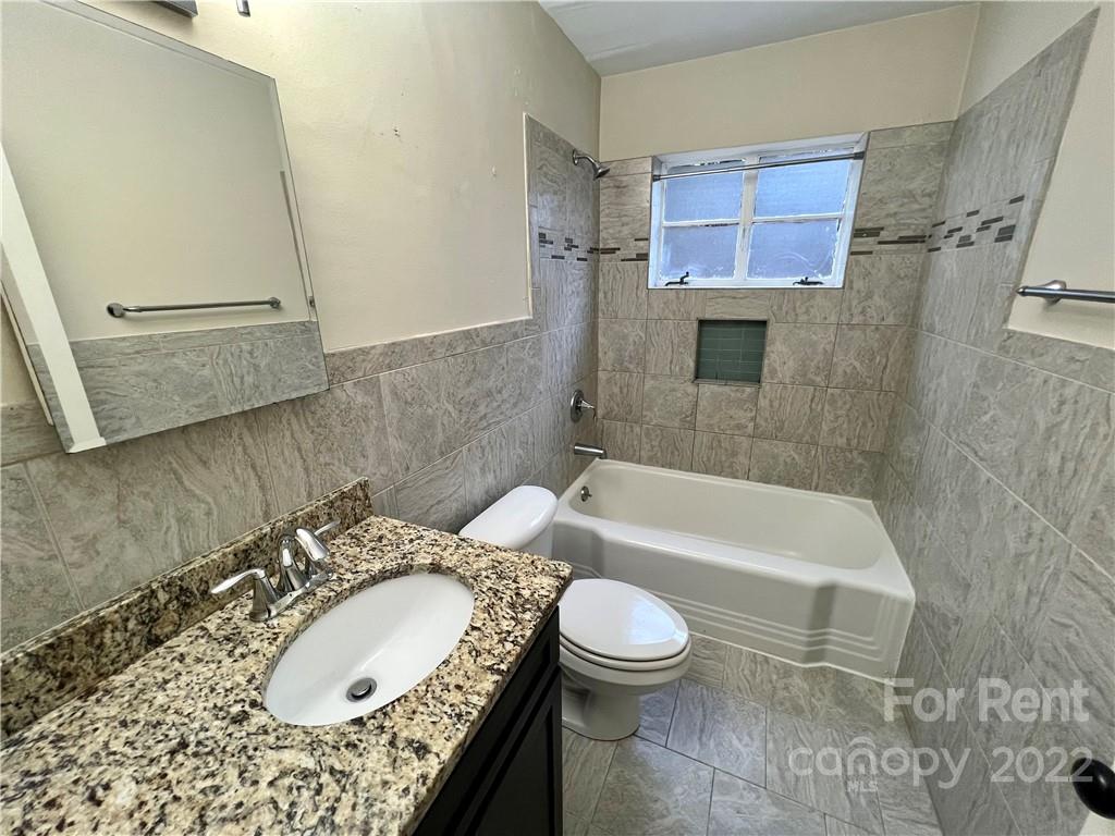 1708 Dilworth Road West, Unit 2 Charlotte, NC 28203 - Photo 6 of 8 a bathroom with a granite countertop bathtub sink mirror vanity and toilet