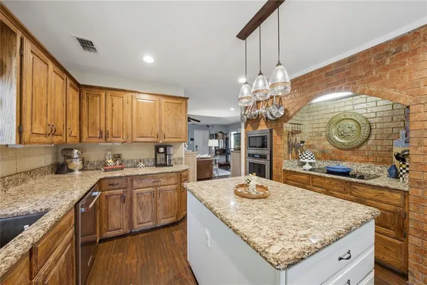 a kitchen with stainless steel appliances kitchen island granite countertop a stove a sink and a refrigerator