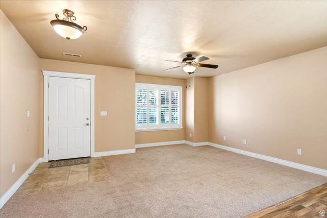 1089 West 2325th Street North Layton, UT 84041 - Photo 4 of 40 Entryway and living area featuring a neutral color palette, carpet flooring, a window with plantation shutters, a ceiling fan, and tile flooring at the entry