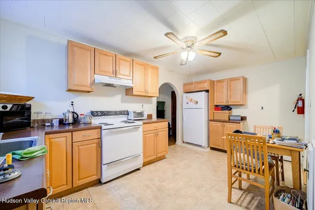 a kitchen with stainless steel appliances granite countertop a refrigerator a stove a sink dishwasher and white cabinets with wooden floor