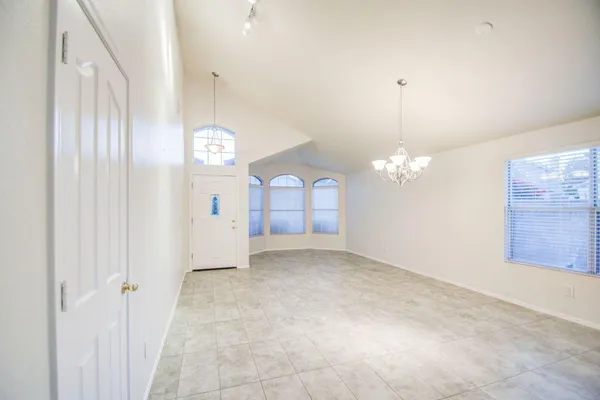 an empty room with chandelier fan and windows