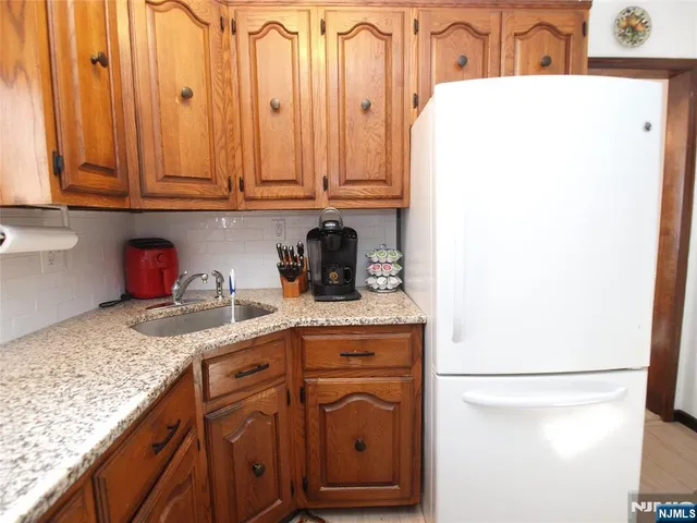 a kitchen with granite countertop a sink a stove and a refrigerator