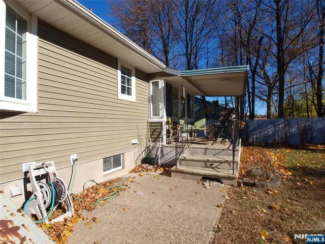 a view of a patio with table and chairs under an umbrella with large tree