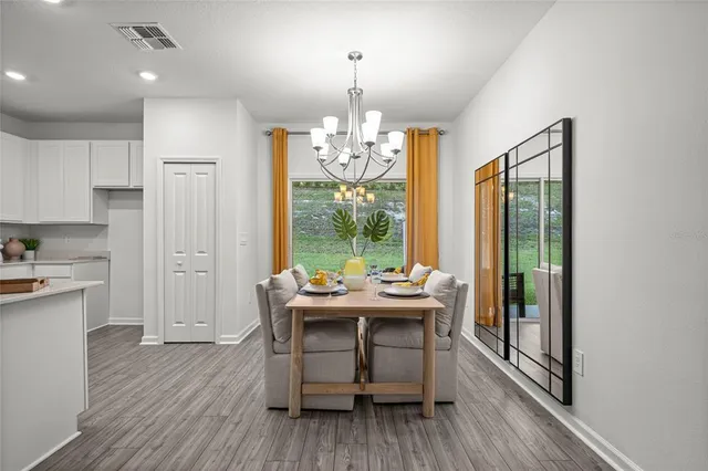 a dining room with wooden floor a chandelier a wooden table and chairs