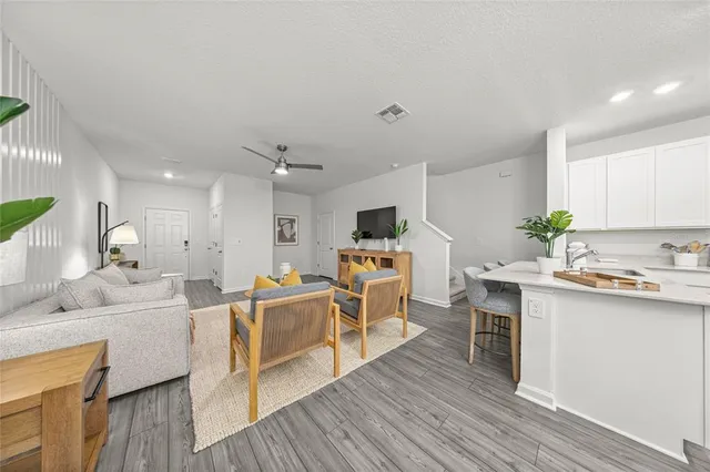 a living room with stainless steel appliances kitchen island furniture a wooden floor and a sink