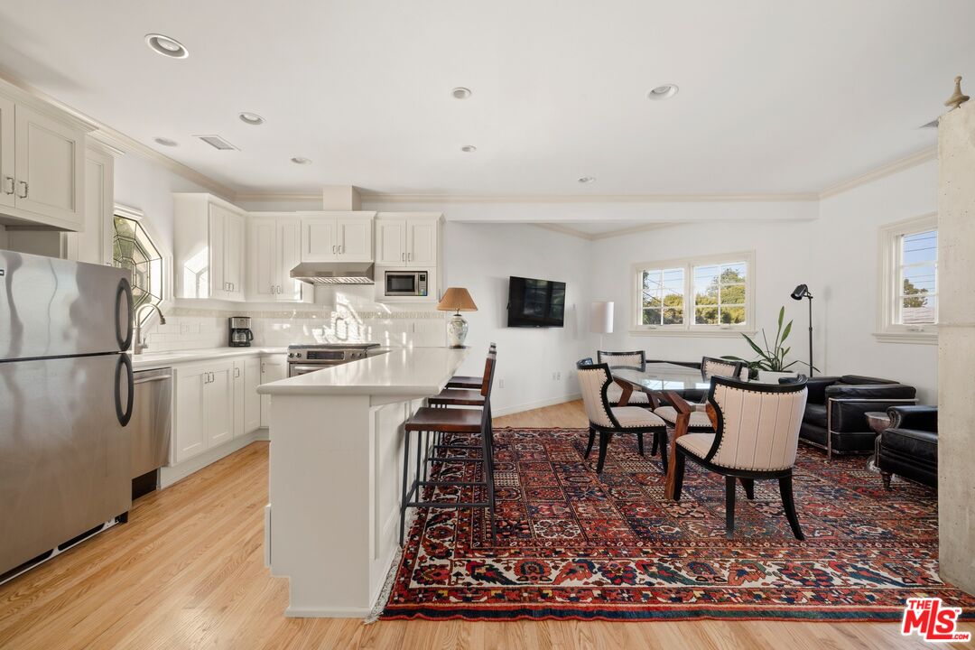 524 North Rockingham Avenue Los Angeles, CA 90049 - Photo 18 of 24 a kitchen with stainless steel appliances granite countertop a sink a stove a refrigerator cabinets and a dining table