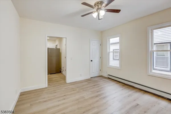 an empty room with wooden floor closet and windows