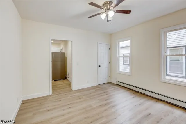 an empty room with wooden floor closet and windows