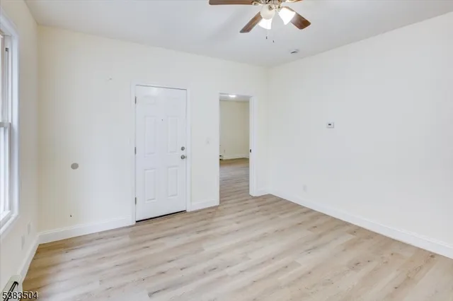 an empty room with a ceiling fan and wooden floor