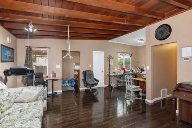 a living room with couches and kitchen view with wooden floor