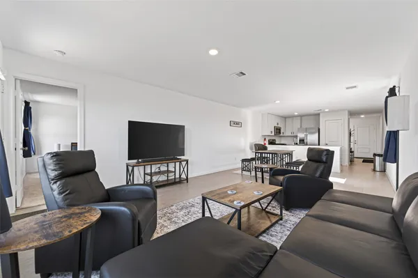 a living room with furniture kitchen view and a flat screen tv