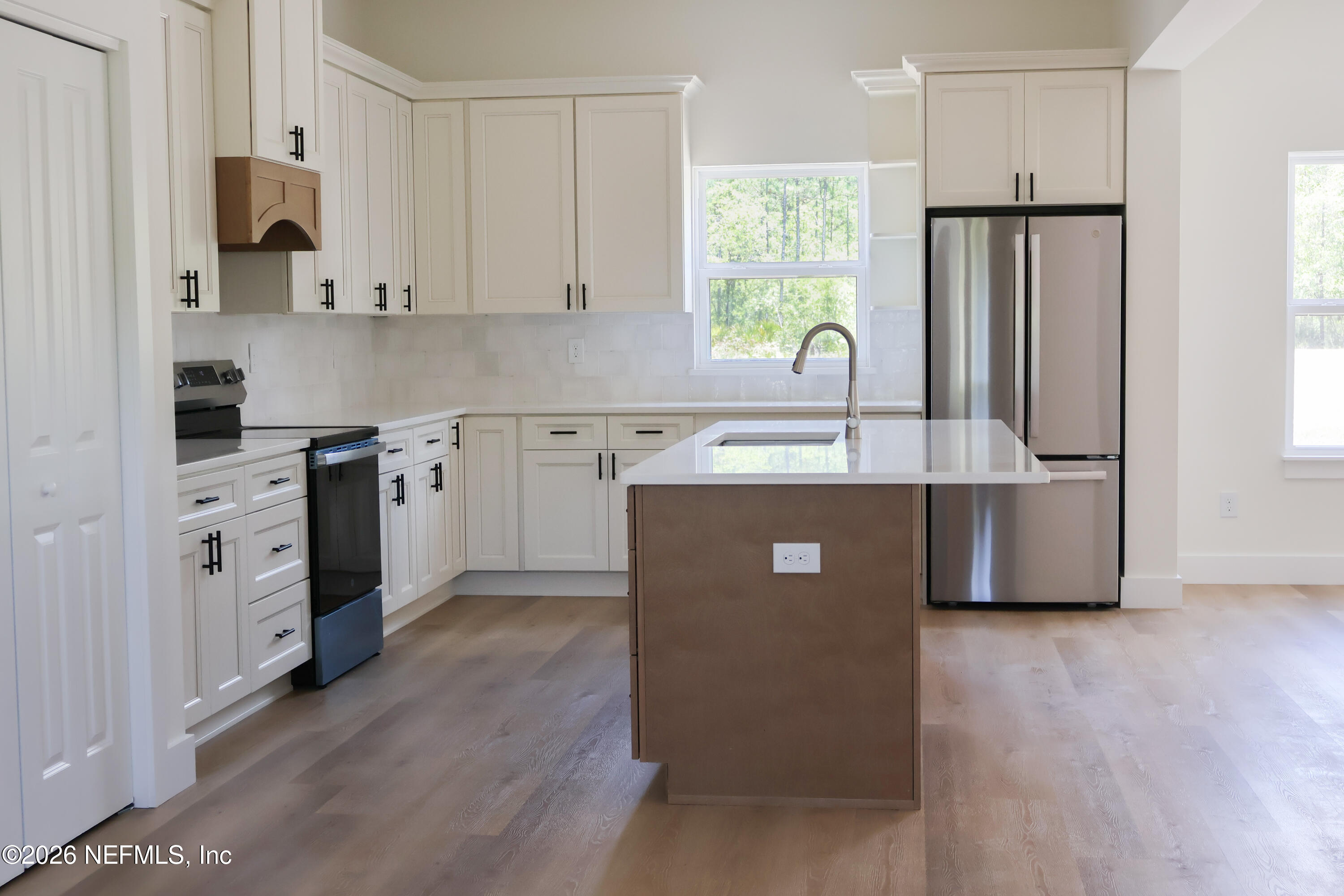 261121 Rowe Road Hilliard, FL 32046 - Photo 11 of 33 a kitchen with stainless steel appliances white cabinets a sink a stove a refrigerator and a window