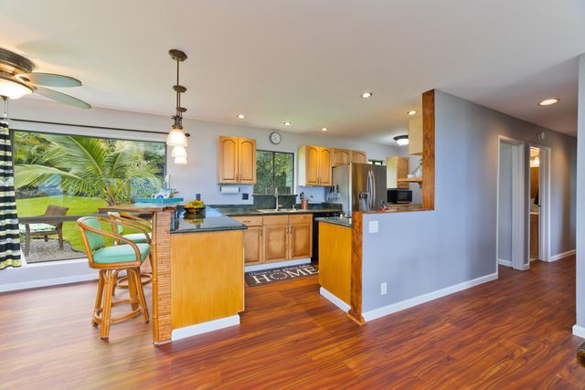 a kitchen with stainless steel appliances granite countertop wooden floors and a view of living room