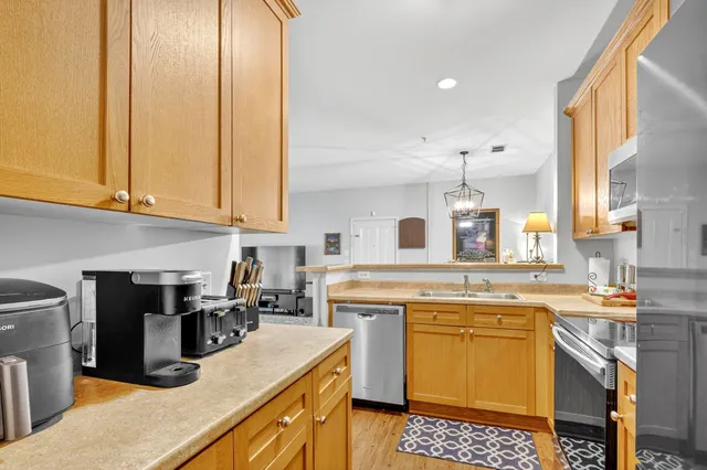a kitchen with kitchen island a stove a sink dishwasher and white cabinets with wooden floor