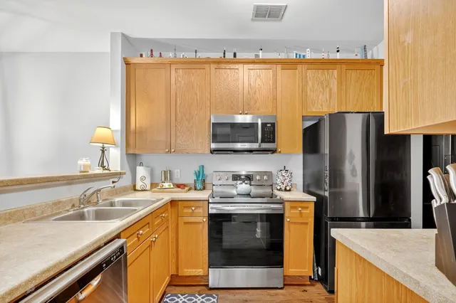 a kitchen with stainless steel appliances a sink dishwasher stove refrigerator and microwave with wooden floor