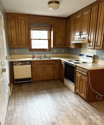 a kitchen with stainless steel appliances granite countertop wooden cabinets a sink and dishwasher with wooden floor