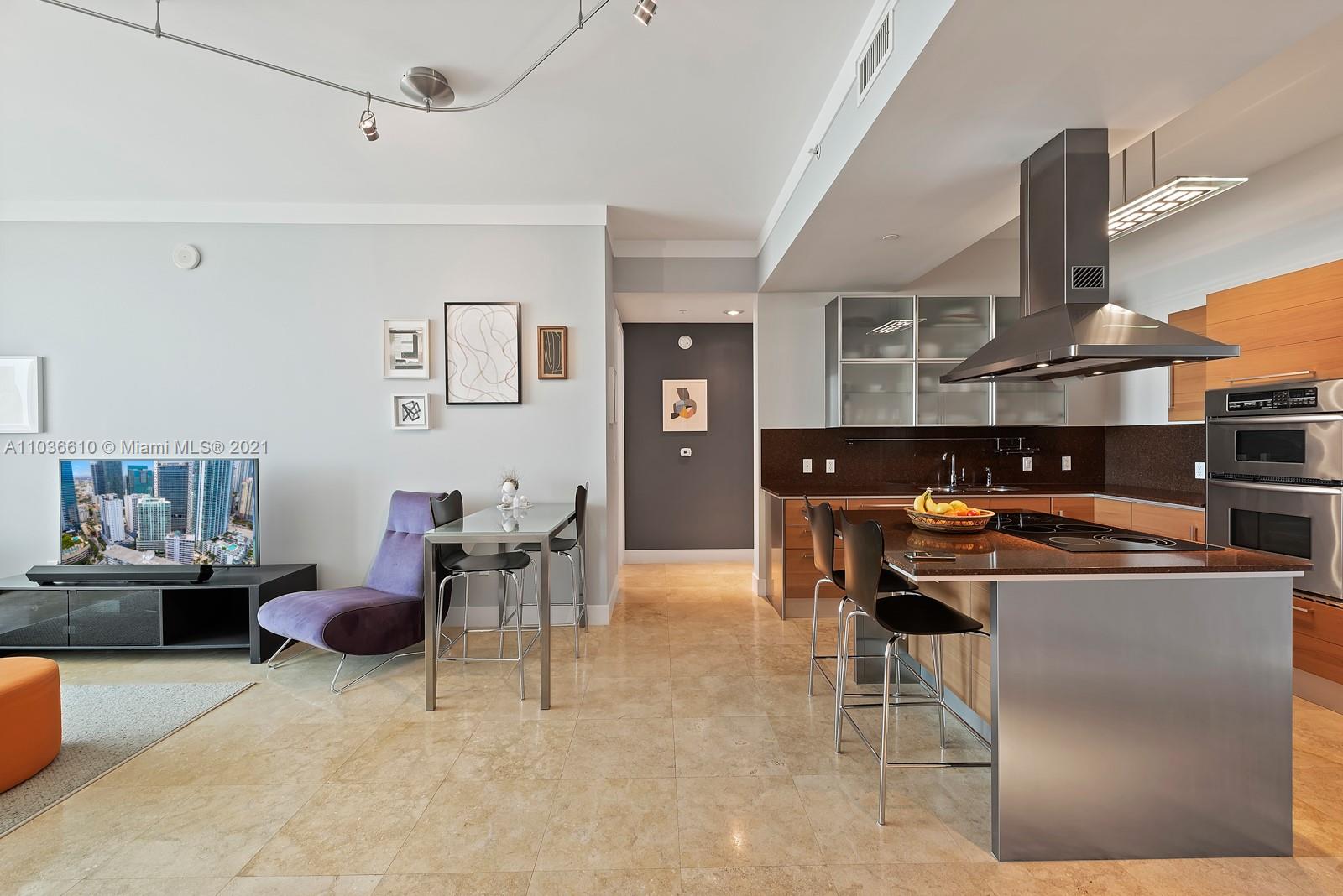 218 Southeast 14th Street, Unit TS103 Miami, FL 33131 - Photo 3 of 31 a kitchen with stainless steel appliances kitchen island granite countertop a table and chairs in it