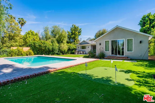 a view of pool with a big yard and potted plants