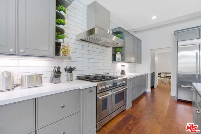 a kitchen with stainless steel appliances granite countertop wooden cabinets a stove a sink and a wooden floor