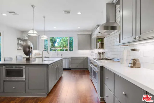 a kitchen with stainless steel appliances granite countertop a sink a stove and a wooden floors
