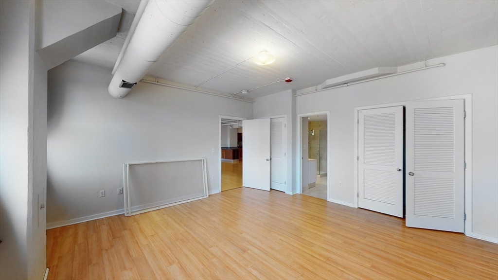 210 South Street, Unit 104 Boston, MA 02111 - Photo 15 of 24 an empty room with wooden floor and closet