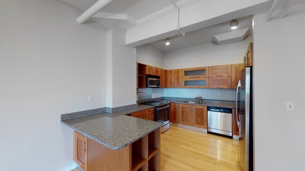 210 South Street, Unit 104 Boston, MA 02111 - Photo 5 of 24 a kitchen with stainless steel appliances granite countertop a sink and a stove