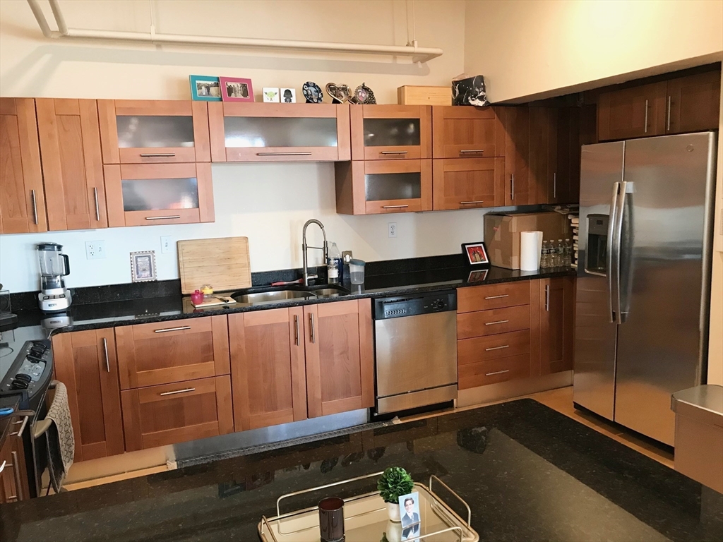 210 South Street, Unit 104 Boston, MA 02111 - Photo 6 of 24 a kitchen with stainless steel appliances granite countertop a refrigerator and a sink