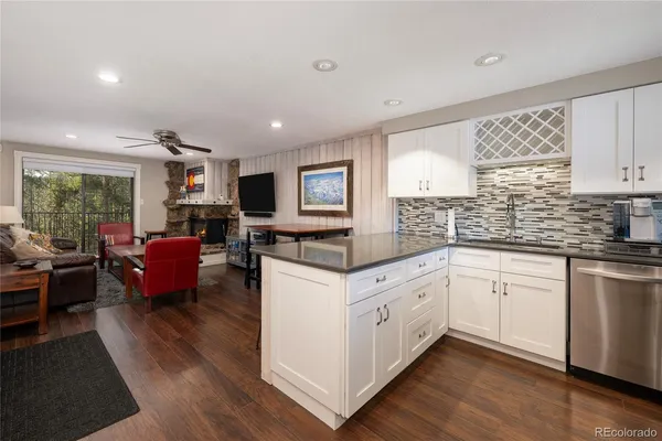 a kitchen with stainless steel appliances granite countertop a stove top oven a sink dishwasher a dining table and chairs with wooden floor