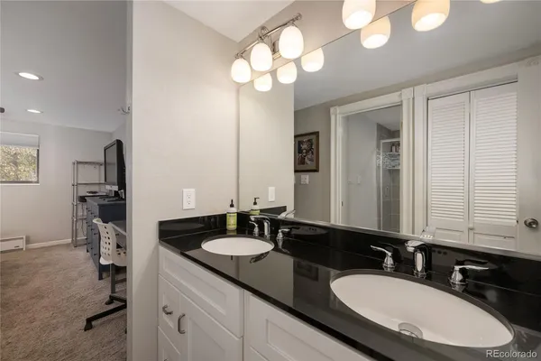 a bathroom with double vanity sinks a vanity a lamp and a mirror
