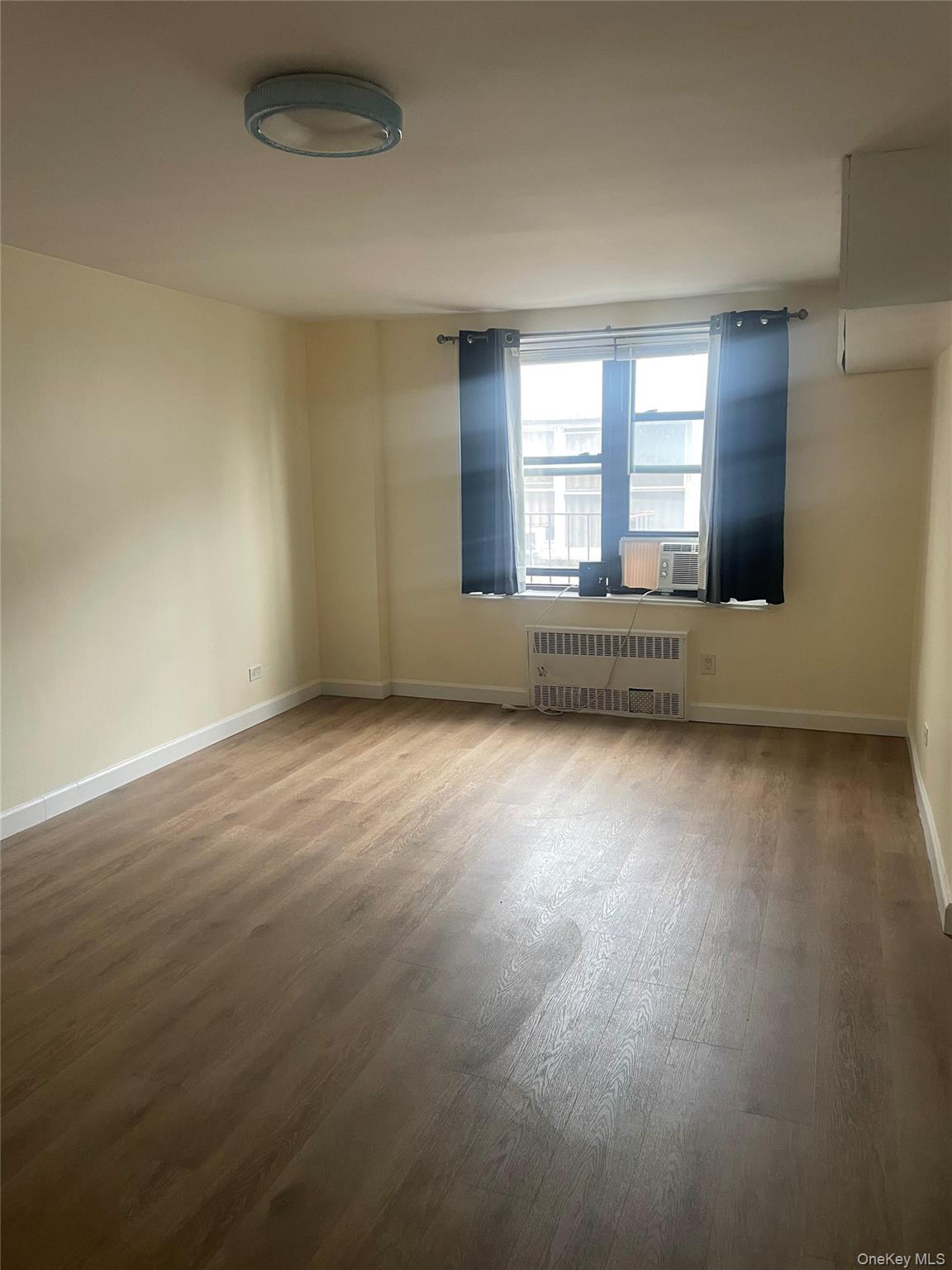 83-85 116th Street, Unit 3F Queens, NY 11418 - Photo 4 of 5 an empty room with wooden floor and windows