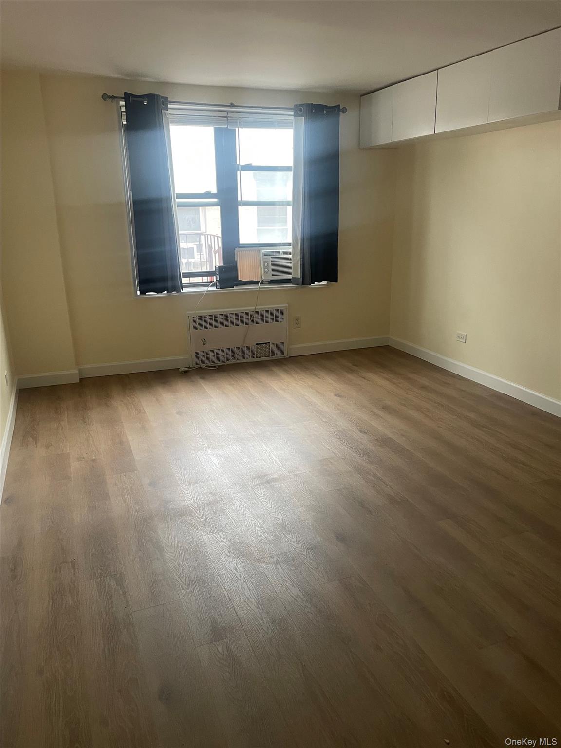 83-85 116th Street, Unit 3F Queens, NY 11418 - Photo 5 of 5 an empty room with wooden floor and windows