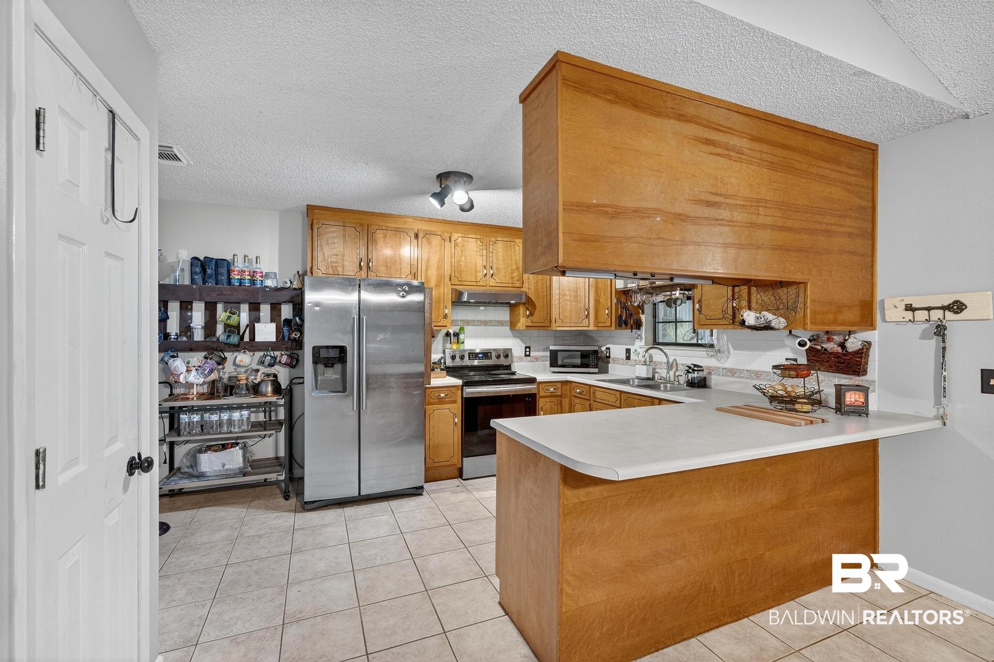21895 2nd Street Silverhill, AL 36576 - Photo 24 of 43 Kitchen with light countertops, a peninsula, light tile flooring, and appliances with stainless steel finishes