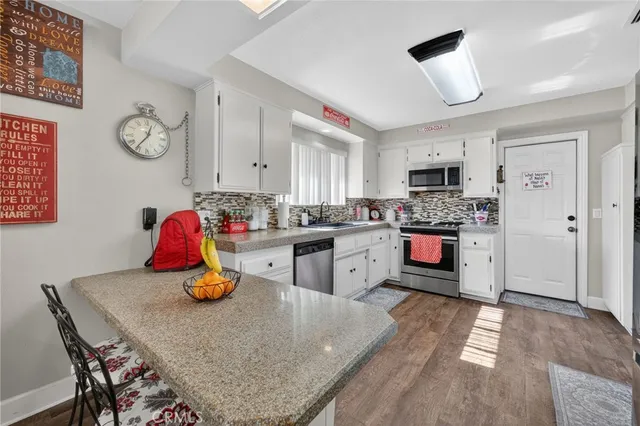 a kitchen with stainless steel appliances granite countertop a stove top oven a sink dishwasher and cabinets with wooden floor