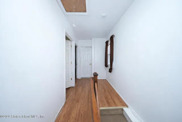 a view of a hallway with wooden floor and a bathroom