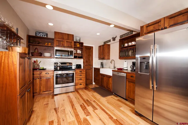 a kitchen with stainless steel appliances granite countertop a refrigerator a stove and a wooden floors