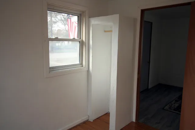 an empty room with wooden floor closet and windows