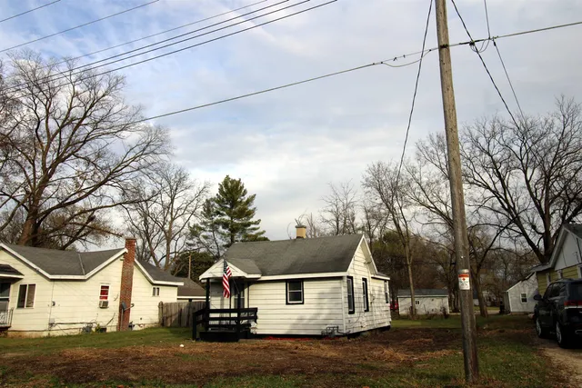 a view of a white house next to a road and yard