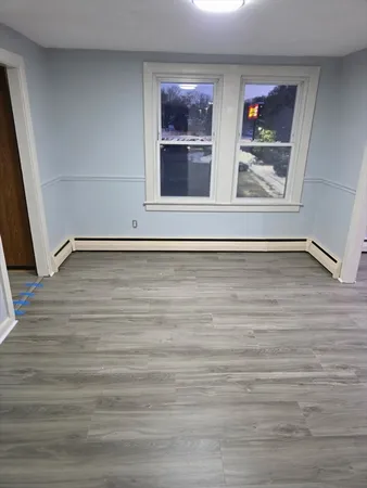a view of an empty room with wooden floor and window