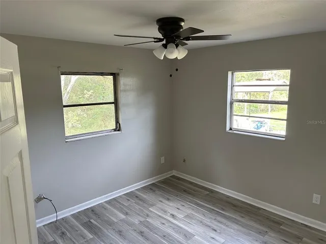 a view of empty room with wooden floor and fan