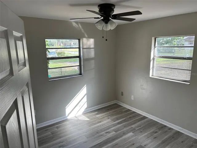 a view of empty room with wooden floor and fan