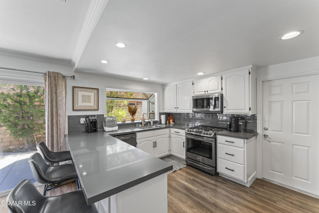 3585 Woodhaven Street Simi Valley, CA 93063 - Photo 5 of 33 a kitchen with stainless steel appliances granite countertop a stove top oven a sink dishwasher and white cabinets with wooden floor