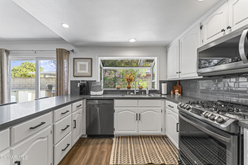 3585 Woodhaven Street Simi Valley, CA 93063 - Photo 6 of 33 a kitchen with stainless steel appliances a white stove top oven a sink and a window