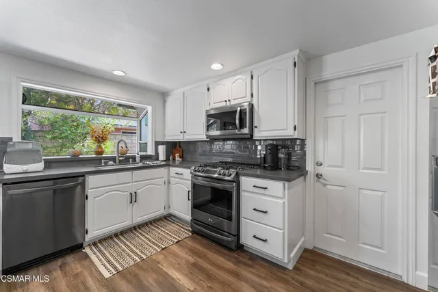 a kitchen with stainless steel appliances granite countertop white cabinets granite counter tops and a window