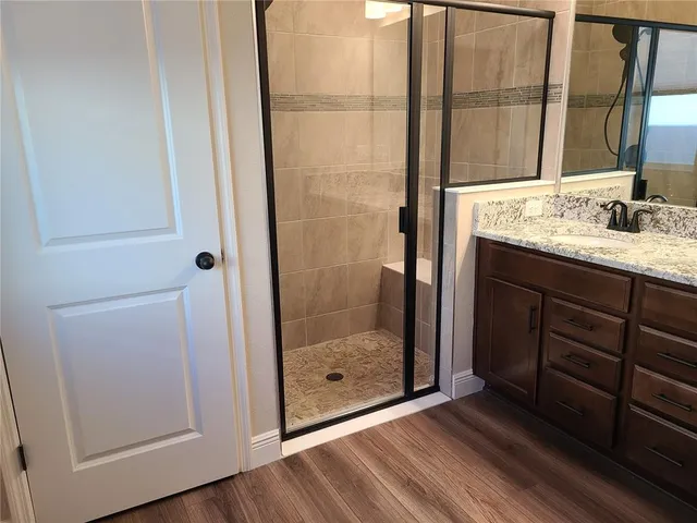 a bathroom with a granite countertop sink a mirror and shower