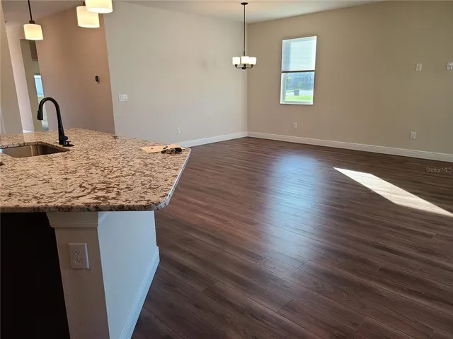 a kitchen with kitchen island granite countertop a sink cabinets and wooden floor