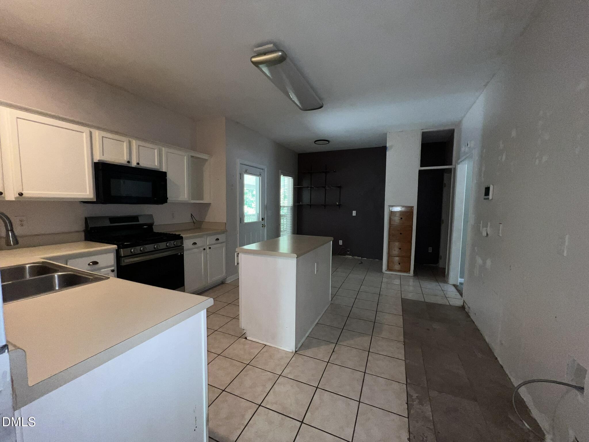 1016 Flower Round Court Raleigh, NC 27610 - Photo 3 of 23 Kitchen featuring white cabinetry, a central island, stainless steel sink, and a black range with an overhead microwave