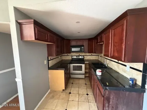 a kitchen with stainless steel appliances granite countertop a refrigerator a stove and a sink with wooden cabinets