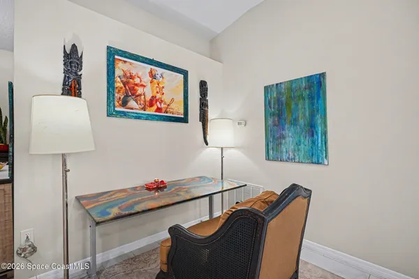 a room with furniture wall paintings and a lamp on dresser